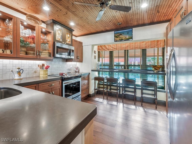 kitchen featuring wood ceiling, ceiling fan, stainless steel appliances, dark hardwood / wood-style floors, and tasteful backsplash