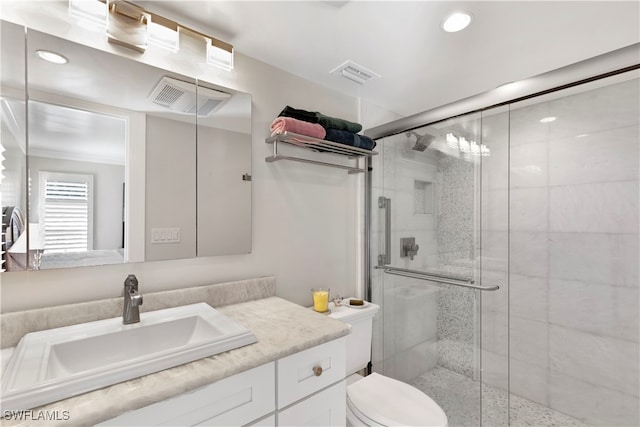 bathroom with a shower with door, vanity, and toilet