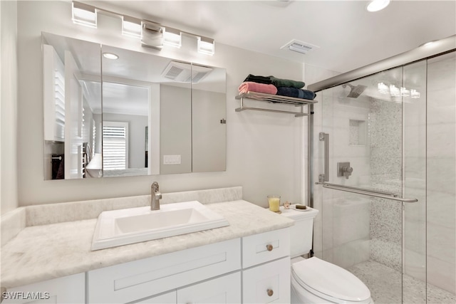 bathroom featuring a shower with door, vanity, and toilet