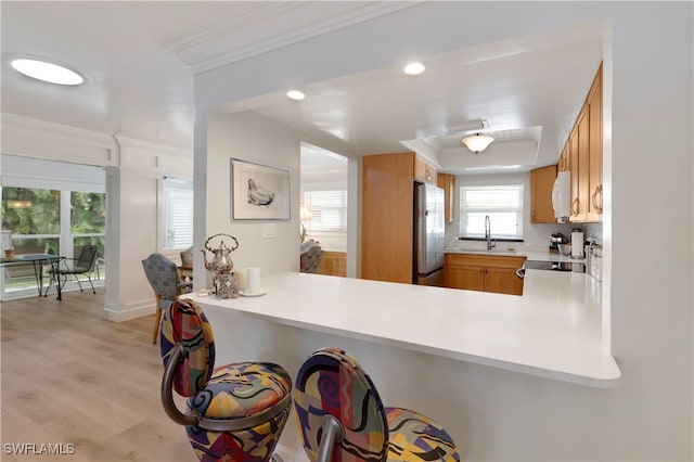 kitchen featuring light wood-type flooring, appliances with stainless steel finishes, decorative backsplash, sink, and kitchen peninsula