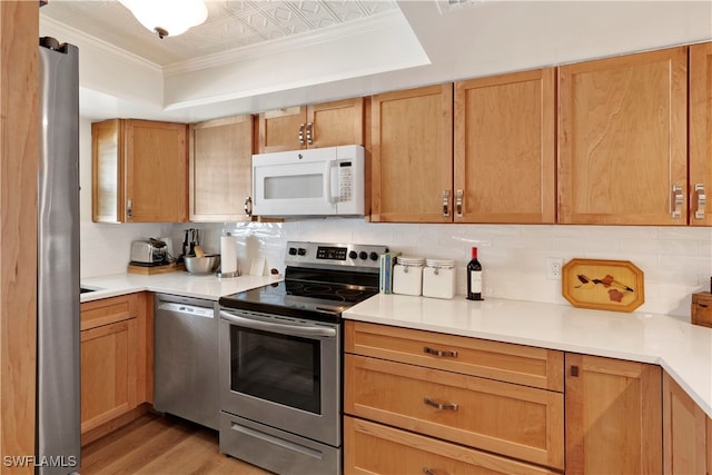 kitchen featuring decorative backsplash, appliances with stainless steel finishes, light hardwood / wood-style floors, and crown molding