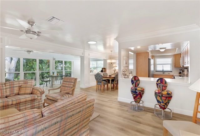 living room with ceiling fan, light hardwood / wood-style floors, a healthy amount of sunlight, and crown molding