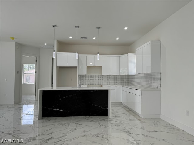 kitchen featuring an island with sink, sink, decorative light fixtures, white cabinets, and tasteful backsplash