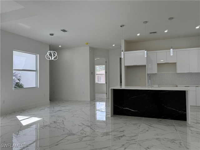 kitchen with hanging light fixtures, a wealth of natural light, decorative backsplash, and white cabinets