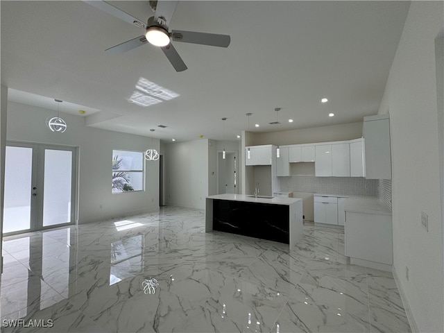 kitchen featuring sink, white cabinets, hanging light fixtures, and an island with sink