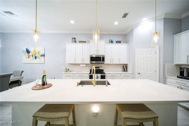 kitchen featuring appliances with stainless steel finishes, a center island with sink, hanging light fixtures, and sink