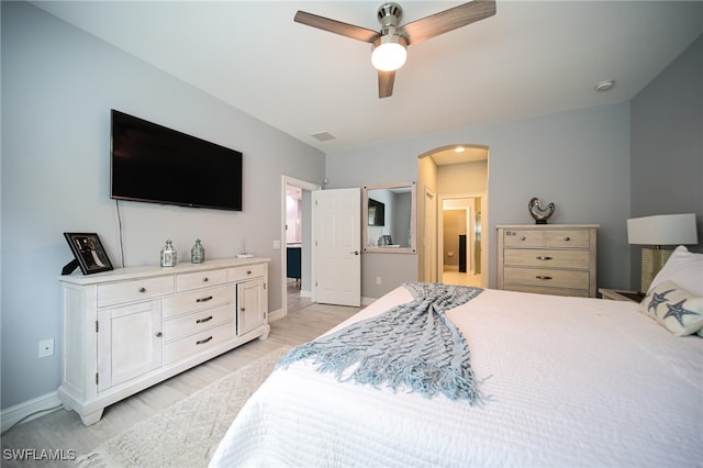 bedroom featuring ceiling fan, light wood-type flooring, and ensuite bath