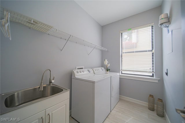 clothes washing area featuring washing machine and clothes dryer, sink, and cabinets