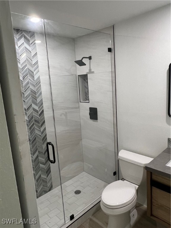 bathroom featuring vanity, an enclosed shower, and toilet