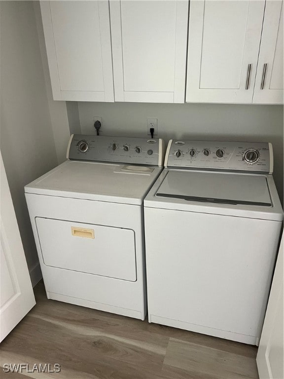 washroom with washer and dryer, hardwood / wood-style flooring, and cabinets