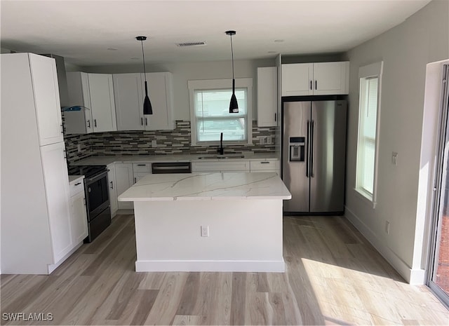 kitchen with sink, a center island, hanging light fixtures, stainless steel appliances, and light stone counters