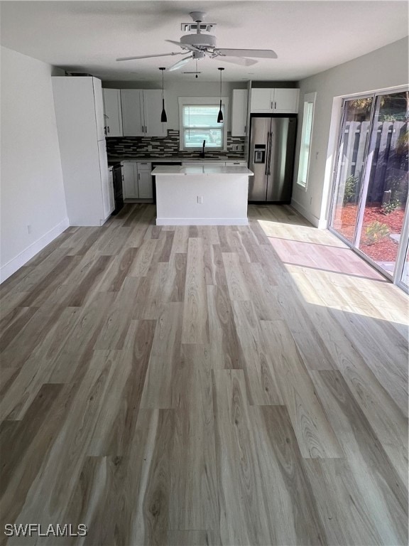 kitchen with a kitchen island, decorative light fixtures, decorative backsplash, light hardwood / wood-style flooring, and stainless steel refrigerator with ice dispenser