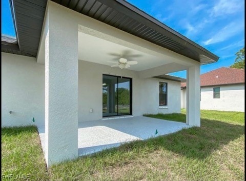 rear view of property featuring a lawn, ceiling fan, and a patio