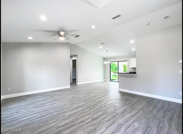 unfurnished living room featuring lofted ceiling, wood-type flooring, and ceiling fan with notable chandelier