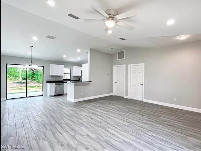 unfurnished living room featuring ceiling fan with notable chandelier, light wood-type flooring, and lofted ceiling