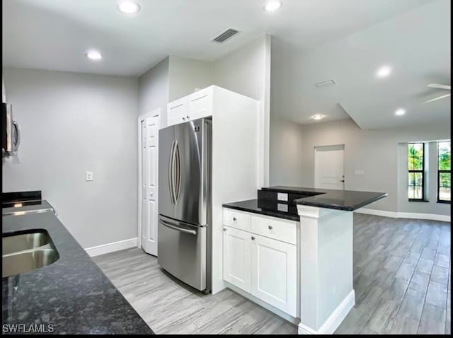 kitchen with sink, kitchen peninsula, appliances with stainless steel finishes, light hardwood / wood-style floors, and white cabinetry