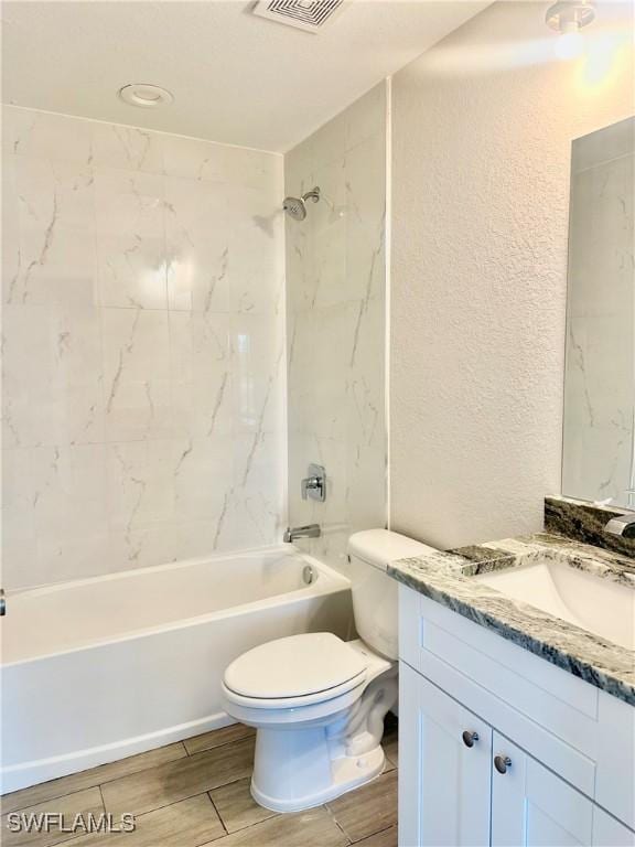 full bathroom with vanity, tiled shower / bath combo, and toilet