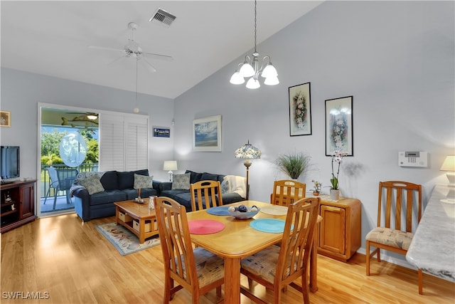 dining area with high vaulted ceiling, ceiling fan with notable chandelier, and light wood-type flooring