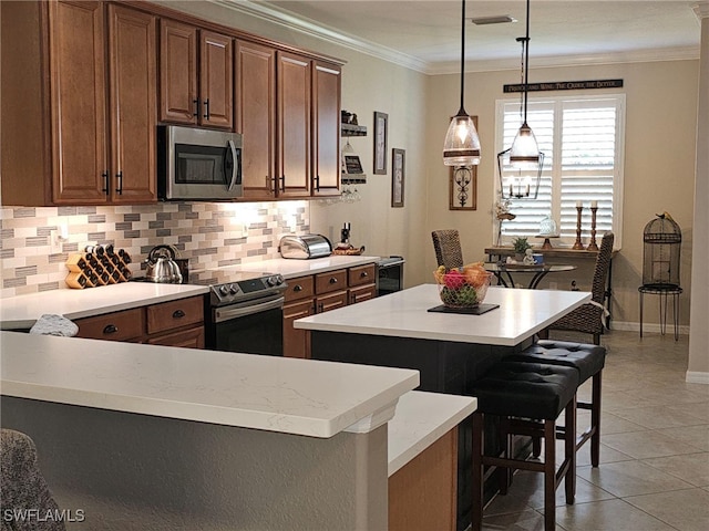 kitchen with light tile patterned floors, appliances with stainless steel finishes, a kitchen island, a kitchen bar, and crown molding