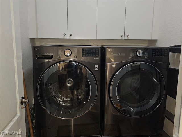 washroom with cabinets and washing machine and clothes dryer