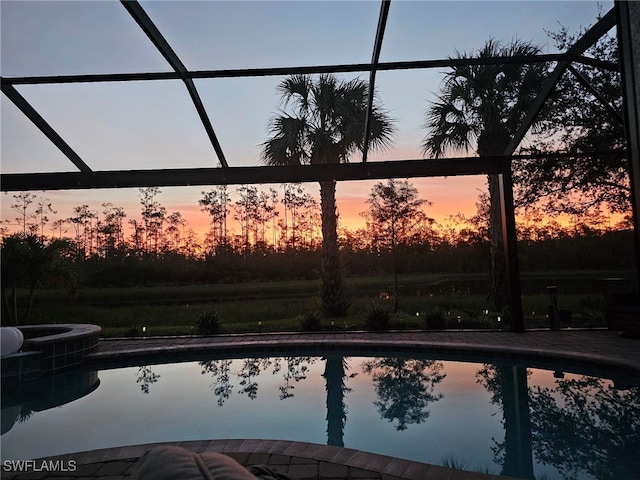 pool at dusk featuring glass enclosure