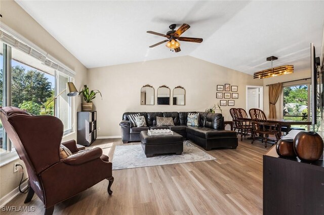 living room with light wood-type flooring, vaulted ceiling, a wealth of natural light, and ceiling fan