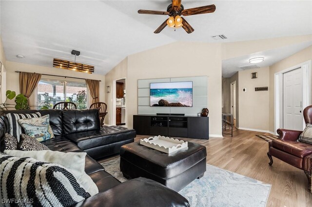 living room with ceiling fan, light wood-type flooring, and vaulted ceiling