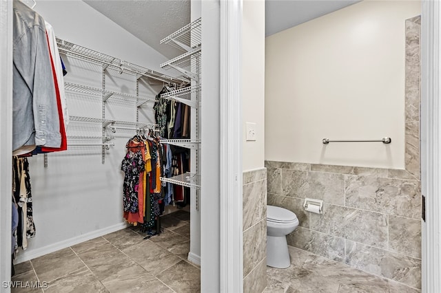 bathroom featuring a textured ceiling, toilet, lofted ceiling, and tile walls