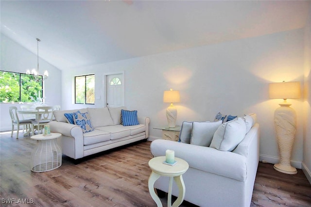 living room with wood-type flooring, vaulted ceiling, and a notable chandelier