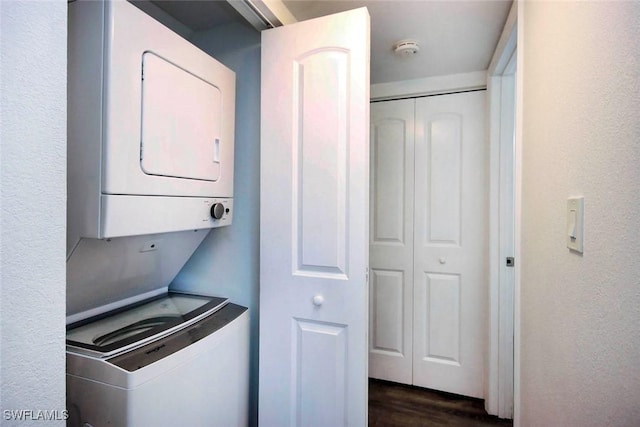 laundry area featuring dark hardwood / wood-style floors and stacked washer / dryer