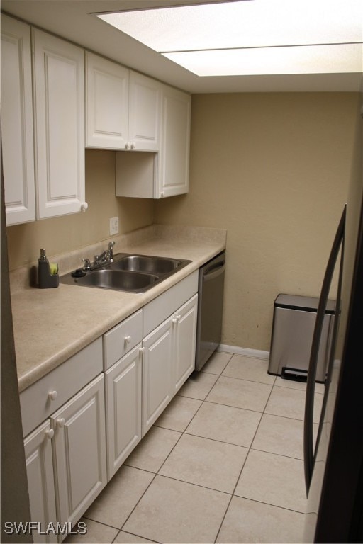 kitchen with dishwasher, sink, light tile patterned flooring, and white cabinets