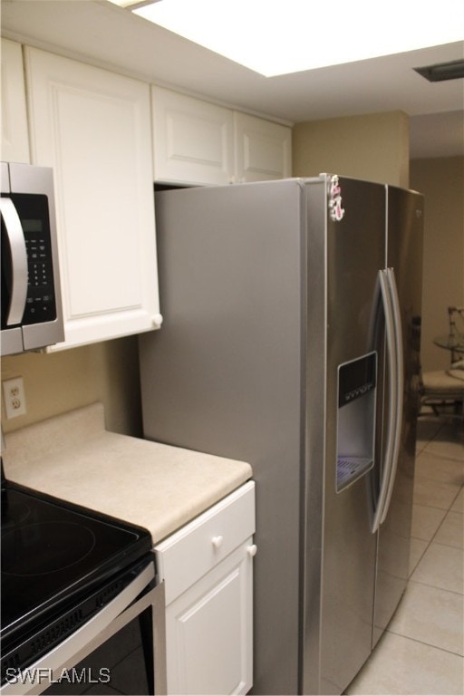 kitchen with white cabinetry, light tile patterned floors, and stainless steel appliances