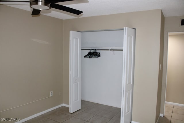 unfurnished bedroom with light tile patterned floors, ceiling fan, and a closet