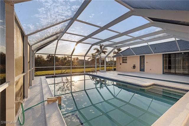 pool at dusk with a patio and a lanai