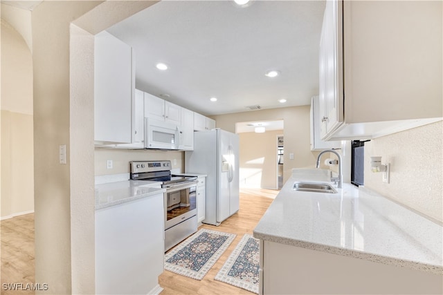 kitchen featuring white cabinets, light stone counters, light hardwood / wood-style floors, sink, and white appliances