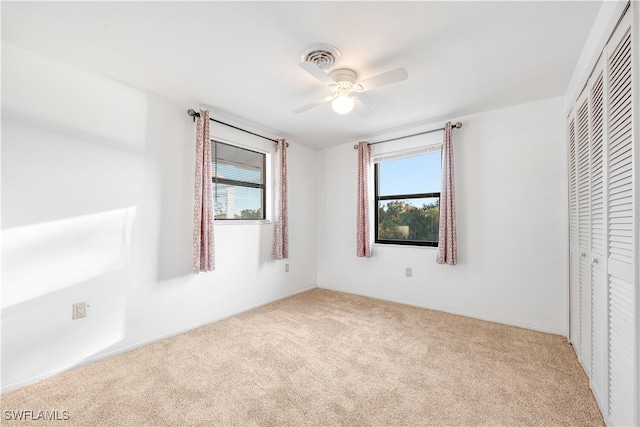 unfurnished bedroom featuring light carpet, a closet, and ceiling fan