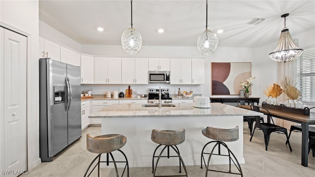 kitchen with an island with sink, white cabinetry, sink, pendant lighting, and stainless steel appliances