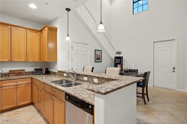 kitchen with kitchen peninsula, hanging light fixtures, stainless steel dishwasher, stone counters, and sink