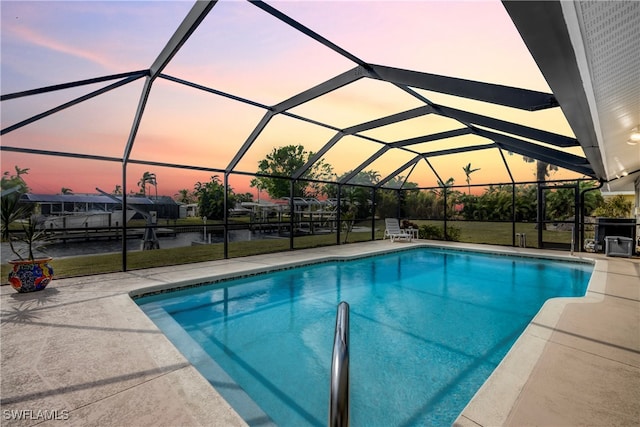 pool at dusk with a water view, a patio, and glass enclosure