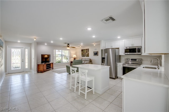 kitchen with a breakfast bar area, sink, white cabinets, appliances with stainless steel finishes, and ceiling fan