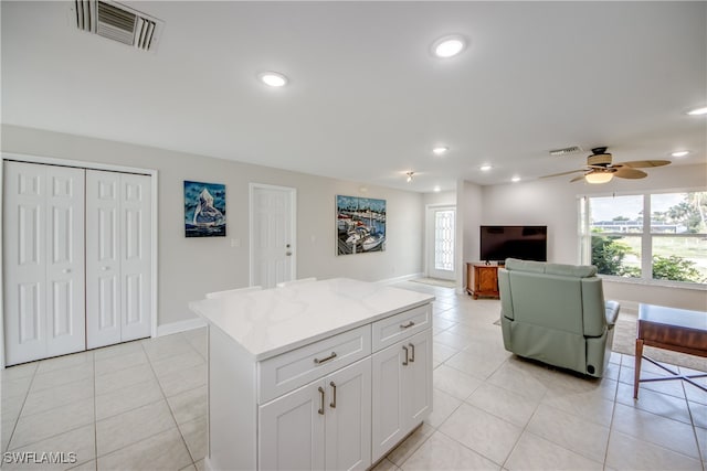 kitchen featuring a kitchen island, white cabinets, light tile patterned flooring, and ceiling fan