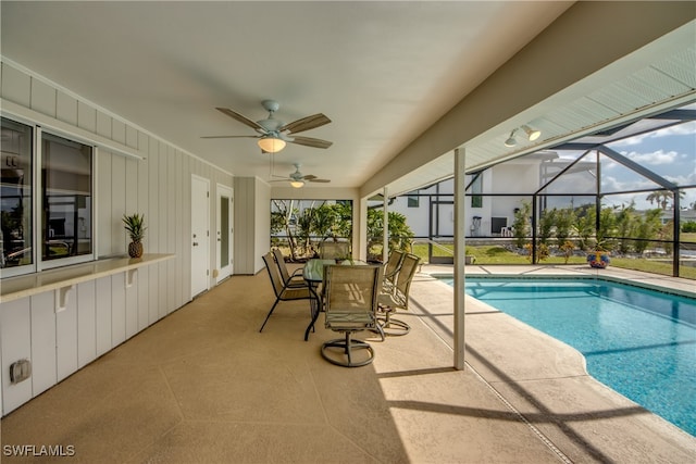 view of swimming pool featuring a patio area, glass enclosure, and ceiling fan