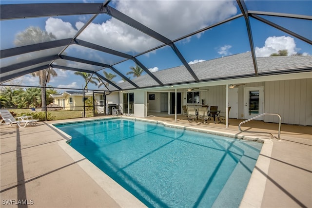 view of swimming pool with a patio, glass enclosure, and ceiling fan