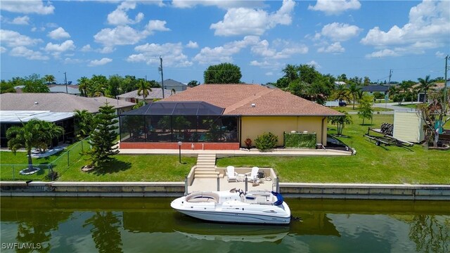 back of house with a water view, a lanai, and a yard