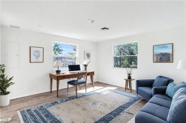 home office featuring wood finished floors, visible vents, and baseboards