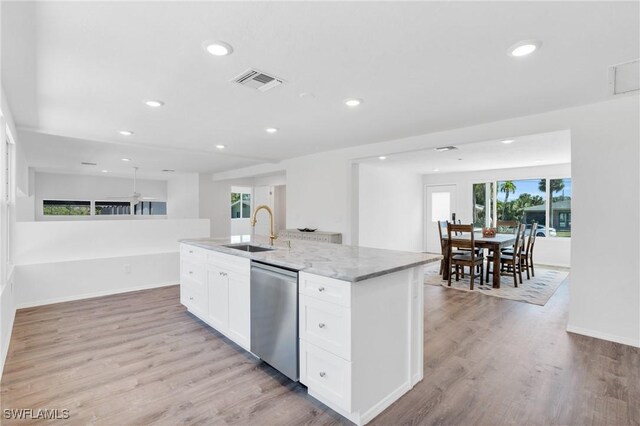 kitchen featuring a sink, white cabinetry, open floor plan, stainless steel dishwasher, and an island with sink