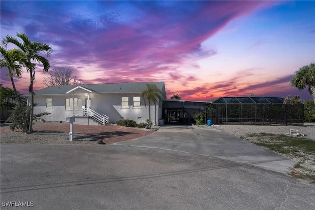 view of front of property featuring glass enclosure, a carport, and stucco siding