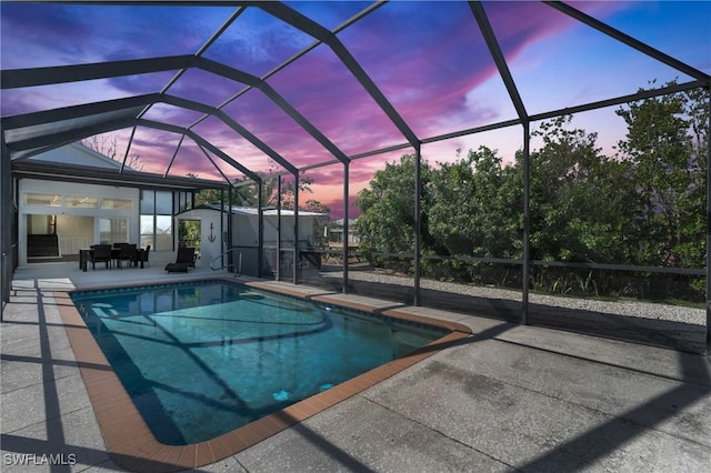 pool at dusk with a lanai, an outdoor pool, and a patio