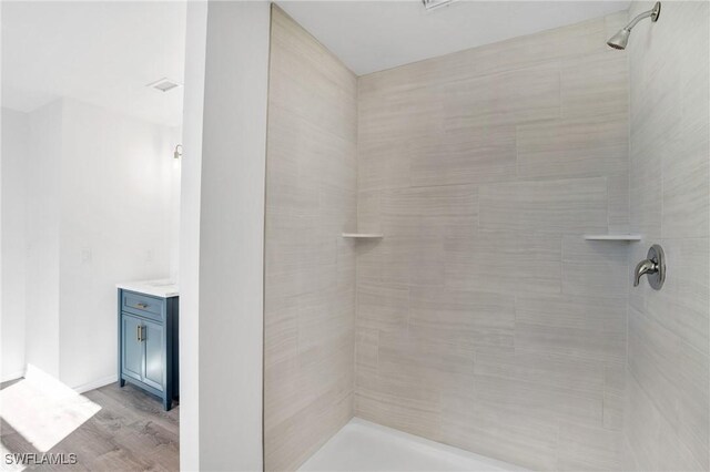 bathroom featuring vanity, tiled shower, and wood finished floors