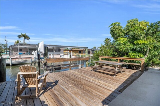 view of dock with a lanai, a water view, and boat lift